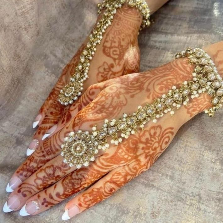 two hands covered in henna with gold and white decorations on top of each hand