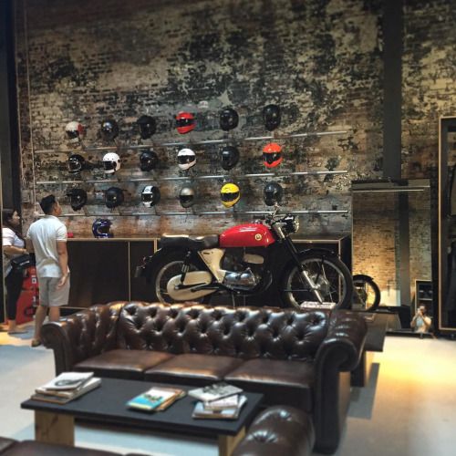 a motorcycle is on display in a room with leather couches and tables, while two men look at it