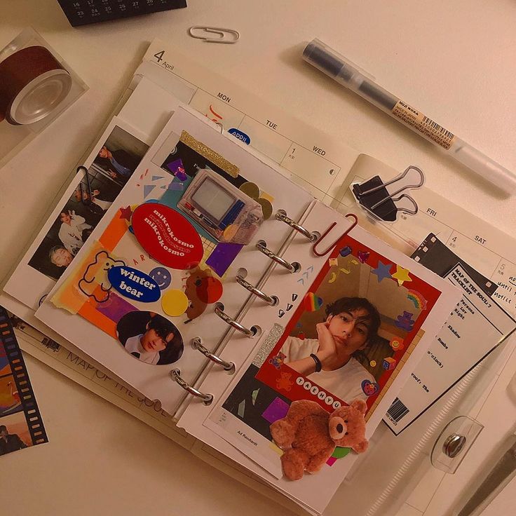 an open planner book with pictures and stickers on it sitting next to a keyboard