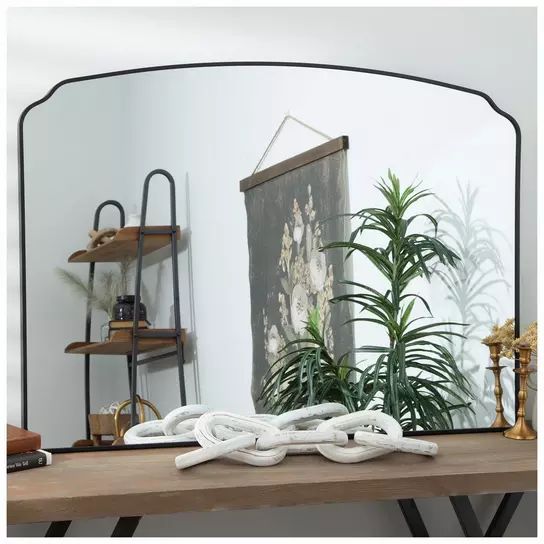 a mirror sitting on top of a wooden table next to a potted plant in front of it