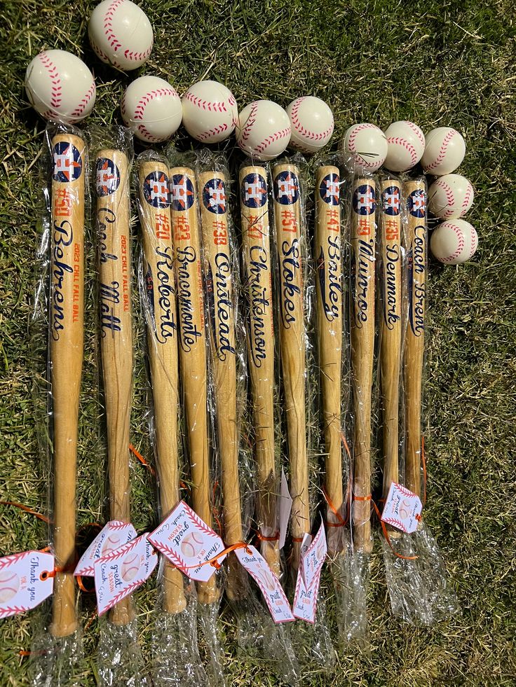 baseballs and bats are lined up in plastic wrap on the grass with tags attached to them