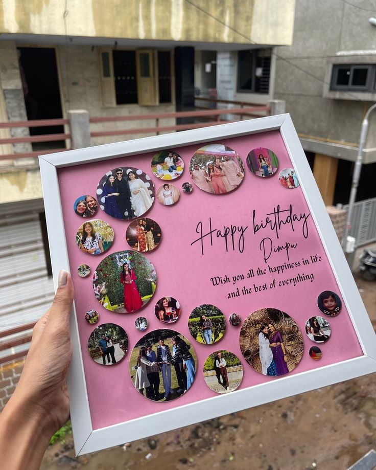 a person holding up a pink frame with pictures on it that says happy birthday daddy