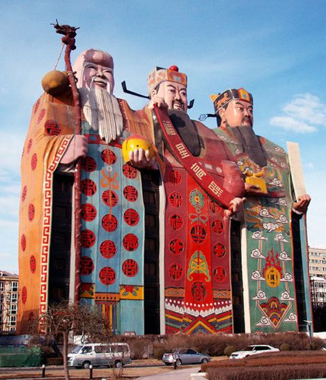 two large statues in front of a building with many different colors and designs on it