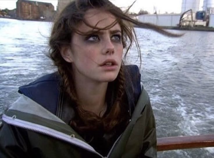 a woman is sitting on a boat in the water and looking off into the distance