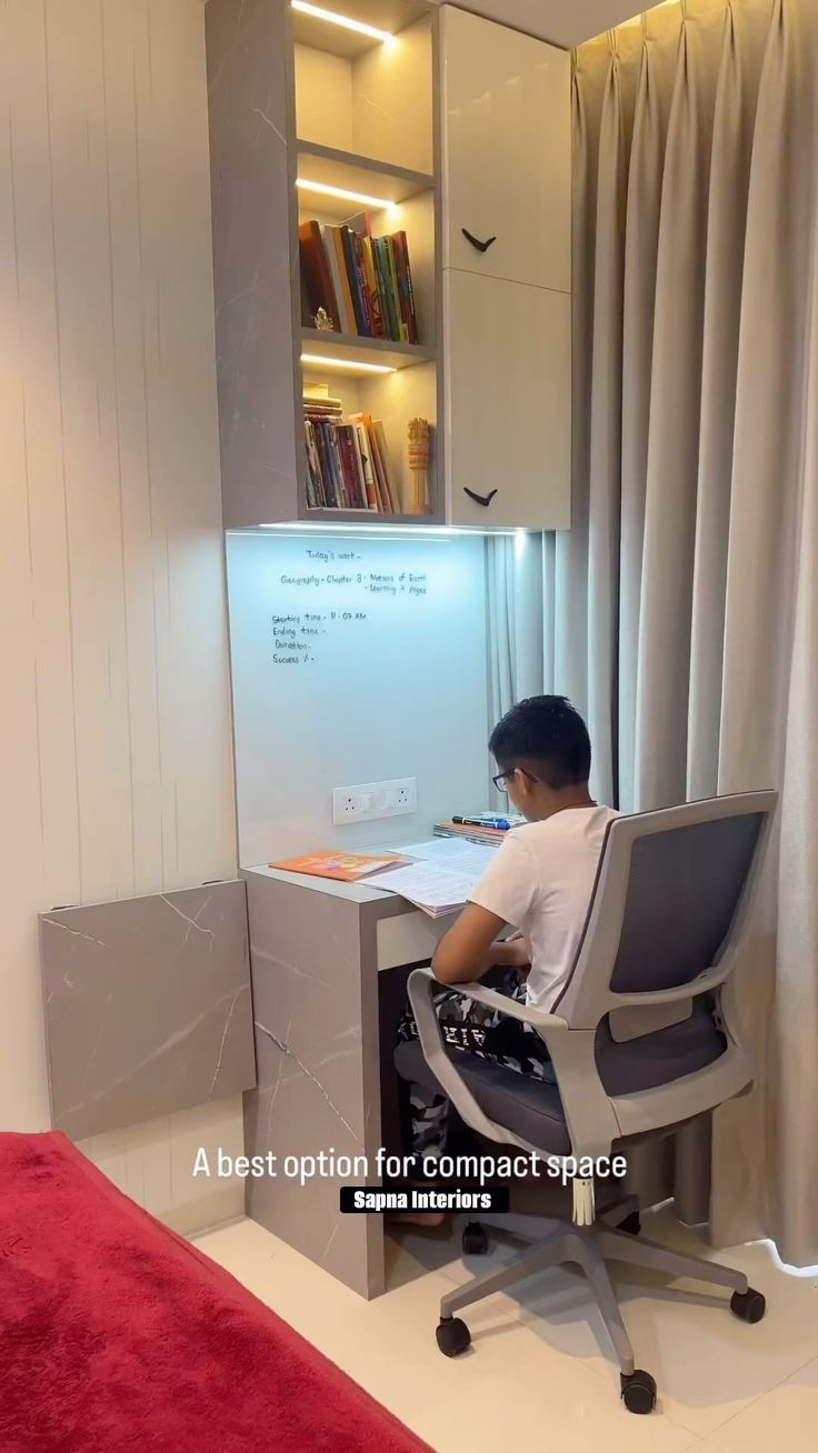 a boy sitting at a desk in front of a book shelf