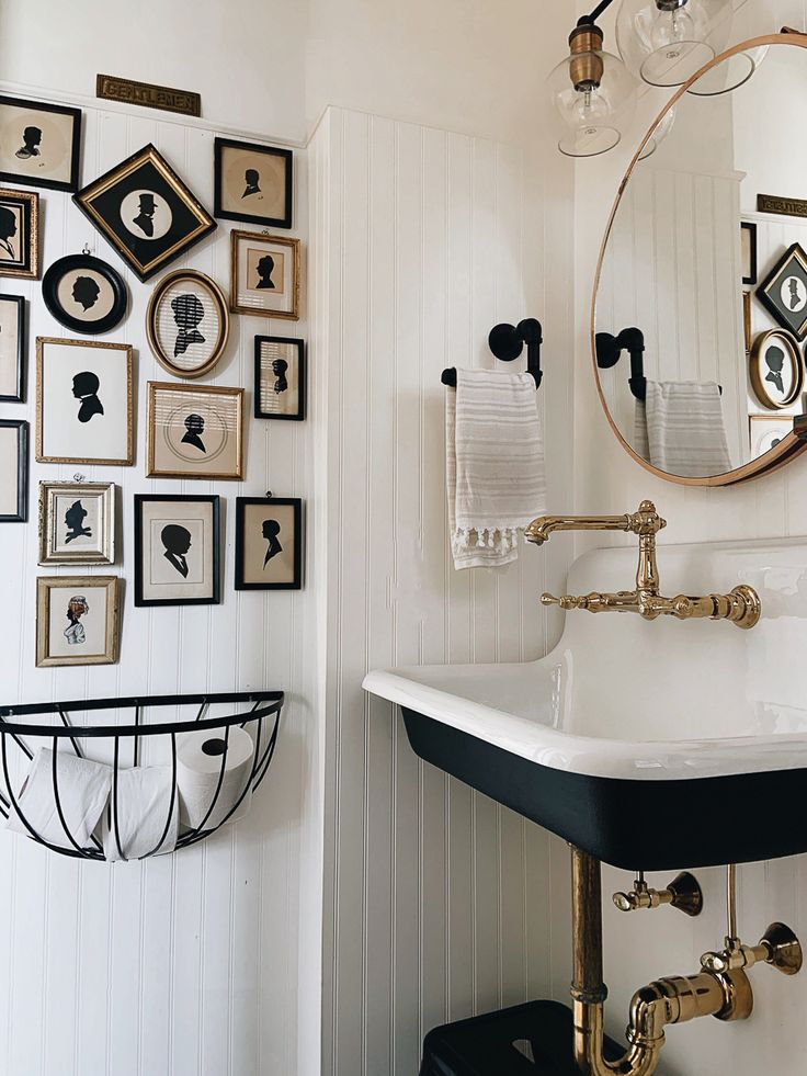 a bathroom sink sitting under a mirror next to a wall with framed pictures on it