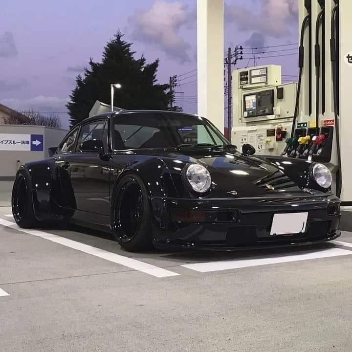 a black porsche parked at a gas station