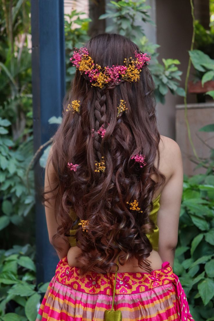 the back of a woman's head with long hair and flowers in her hair