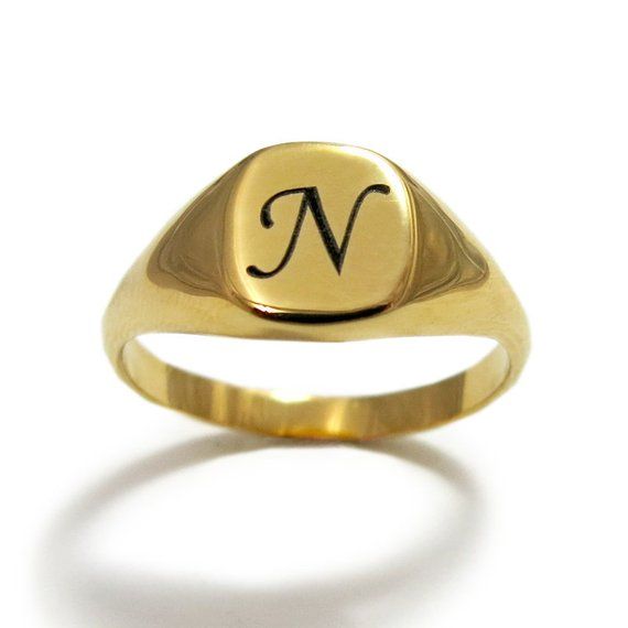 a gold signet ring with the letter n in it's center, on a white background