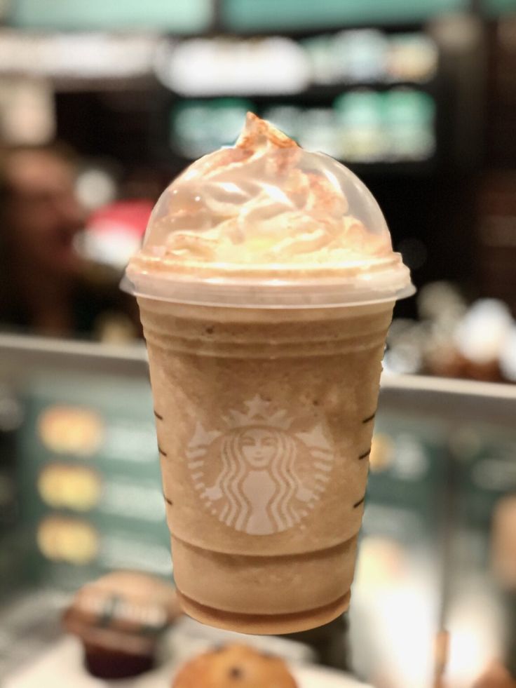 a starbucks drink with whipped cream and cookies on the table in front of some people