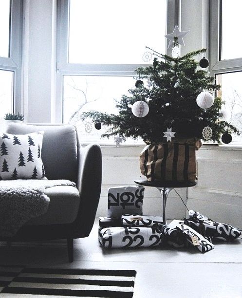 a small christmas tree sitting in the corner of a room next to two couches