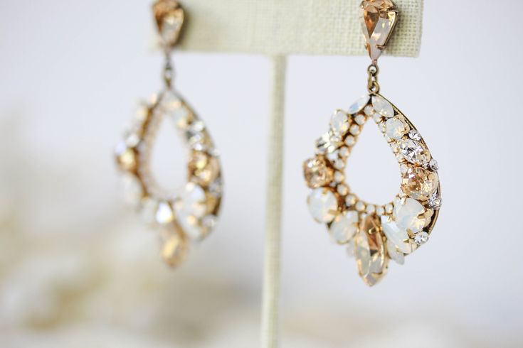 These amazing Swarovski crystal Bridal earrings will take your breath away. An elegant modern design with vintage feel. - Handcrafted with CRYSTALLIZED™ - Swarovski Elements stones - Each stone is set by hand in my studio - Swarovski golden shadow, white opal and clear stones - Antique gold finish - Earrings measure 2 inches x 1.25 inch - Handcrafted in the US. - Nickel free and hypoallergenic - PLEASE ALLOW APPROX 10 BUSINESS DAYS FOR COMPLETION BEFORE SHIPPING. This is an original design by © Elegant Jeweled Hoop Jewelry, Glamorous Crystal Hoop Earrings For Wedding, Sparkling Hoop Jewelry For Wedding, Glamorous Wedding Hoop Earrings With Sparkling Stones, Glamorous Hoop Wedding Jewelry, Elegant Crystal Jeweled Earrings For Wedding, Glamorous Hoop Jewelry For Wedding, Glamorous Sparkling Hoop Earrings For Wedding, Elegant Wedding Crystal Earrings