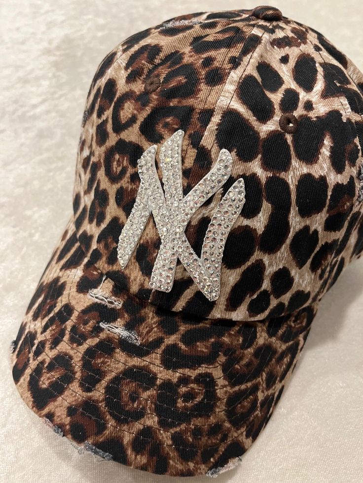 NEW YORK LEOPARD DISTRESSED BLING HAT HAND EMBELLISHED WITH 200+ SWAROVSKI CRYSTALS PRECISE CRYSTAL PLACEMENT ATTENTION TO DETAIL.  THIS HAT DOESN'T LACK BRILLIANCE. ADJUSTABLE BACK STRAP PLEASE FAVORITE MY ETSY SHOP SO YOUR FIRST TO SEE ALL MY CUSTOM HATS https://allabouttheblingcc.etsy.com Winter Hats Outfit, Cheetah Print Accessories, Fitted Cap Outfit Black Women, Cheetah Print Hat Outfit, Bedazzled Fitted Hat, Rhinestone Clothes, Brown Rhinestone Hat, Leopard Ny Hat, Crystal Placement