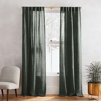 a living room with a chair, window curtain and potted plant in the corner