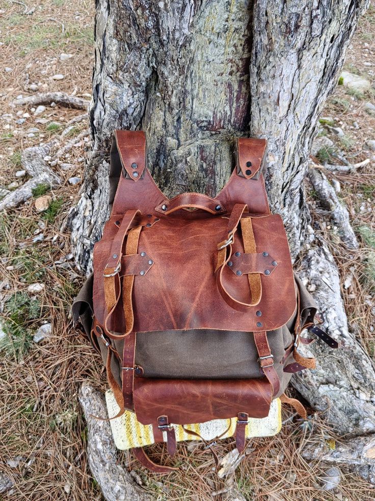 It's a professionally handcrafted Leather backpack for travelers. It's 2mm(5 oz) vegetable-tanned leather. I use it for camping and trekking,hiking. Embrace the wilderness in style with this handcrafted leather backpack, built for adventure. Features More than just a bag, it's your companion on the trail, crafted with premium waxed cotton and designed for ultimate comfort and functionality. Two roomy front pockets keep essentials close at hand, while the dedicated axe hanger with buckle secures Brown Waxed Canvas Bag For Camping, Rugged Bag With Waxed Finish For Outdoor Activities, Rugged Brown Leather Backpack For Outdoor, Brown Waxed Leather Backpack For Outdoor, Rectangular Leather Backpack With Waxed Finish For Outdoor, Rectangular Waxed Leather Backpack For Outdoor, Waxed Canvas Bags For Camping, Rectangular Waxed Leather Backpack, Rugged Rectangular Backpack For Outdoor