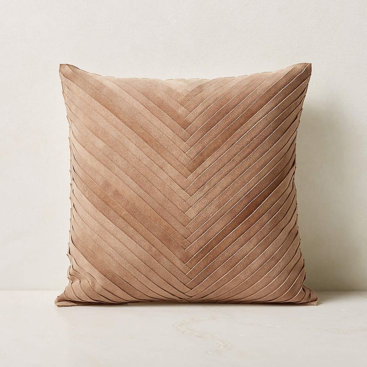 a beige pillow on a white surface