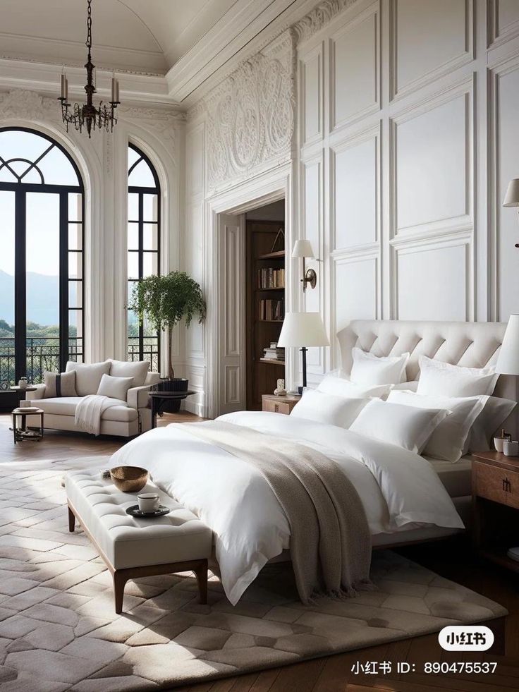 a large white bed sitting in a bedroom next to a window filled with lots of windows