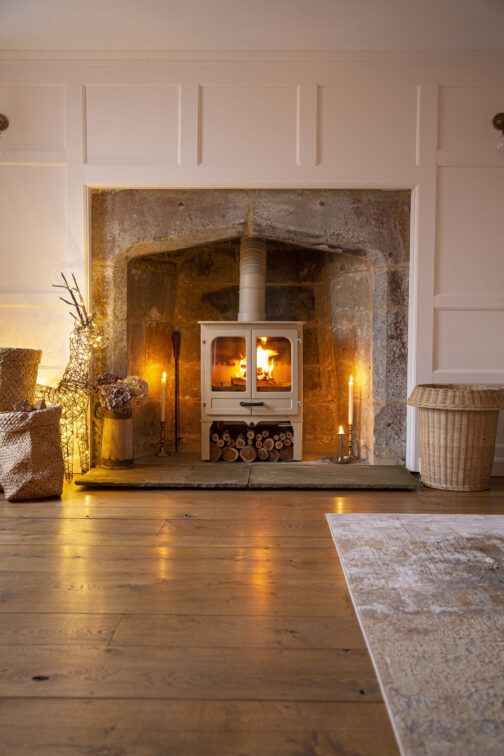 a wood burning stove sitting inside of a living room next to a firewood basket