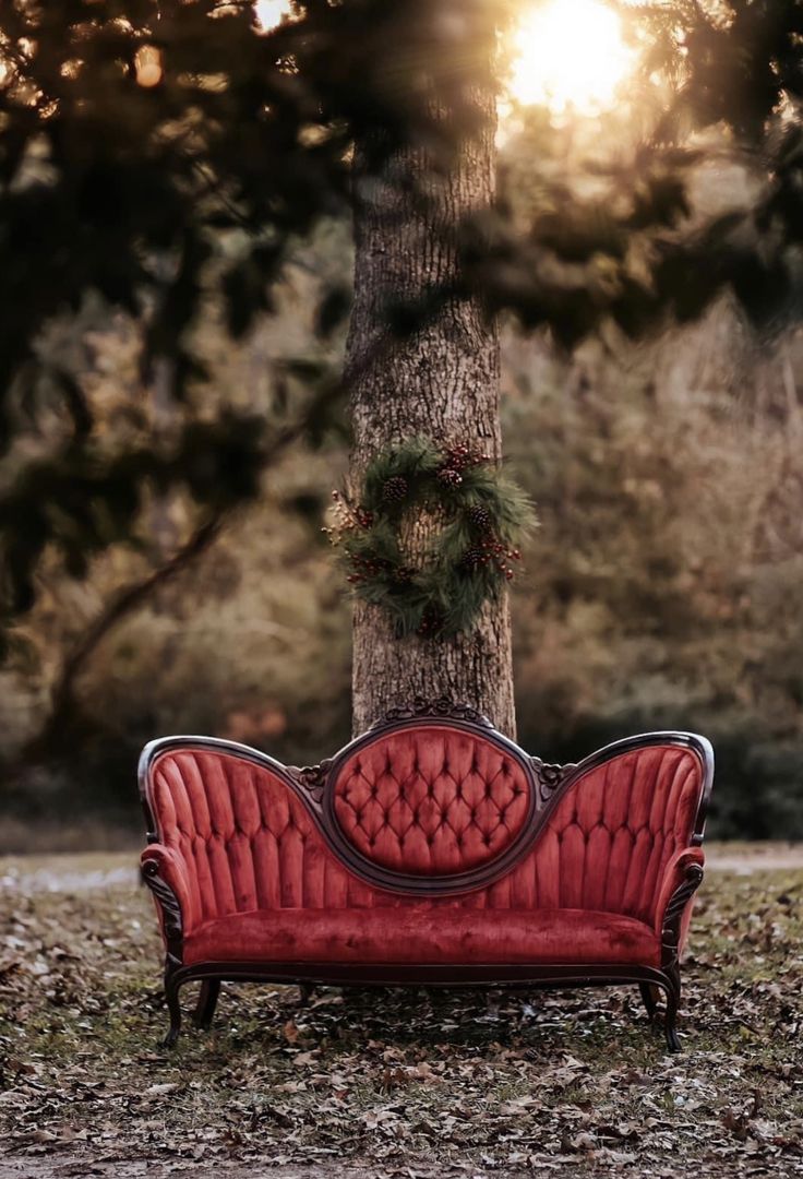 a red couch sitting in front of a tree