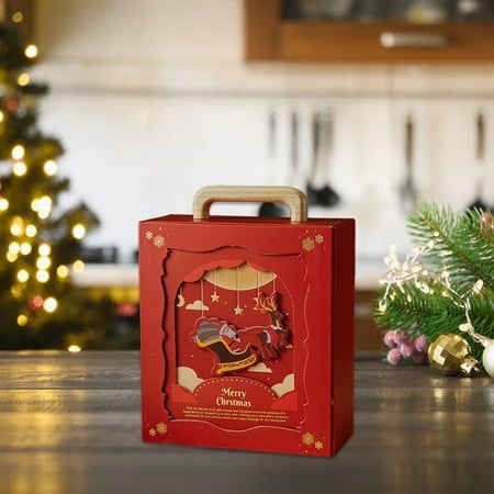 a red box sitting on top of a wooden table next to a christmas tree and decorations