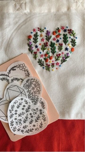 two paper hearts are sitting on top of a piece of fabric next to a card