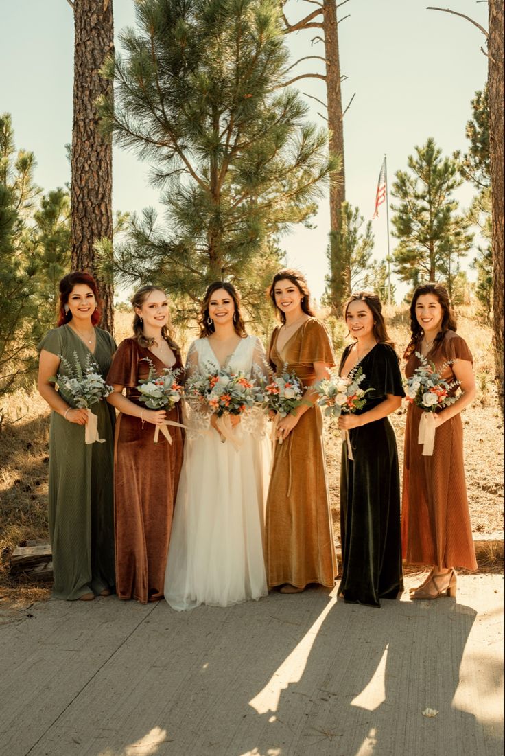 a group of women standing next to each other in front of some tall pine trees