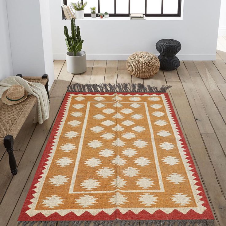 an orange and white rug sitting on top of a wooden floor next to a window