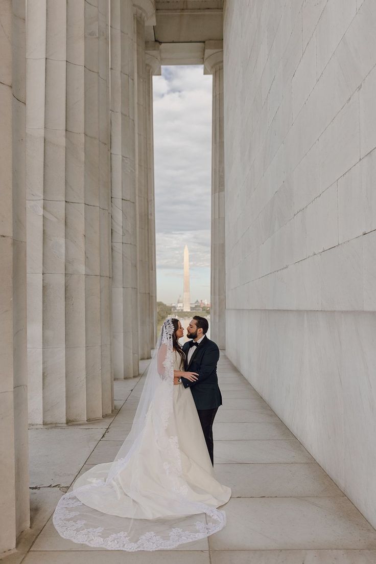 a bride and groom kissing in front of the lincoln memorial