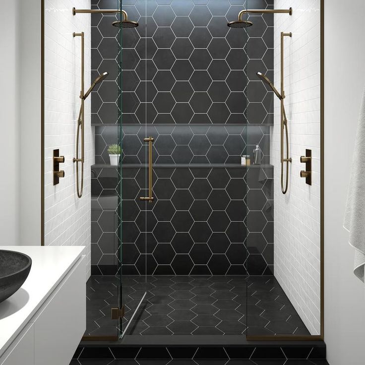 a black and white bathroom with hexagonal tiles on the shower wall, glass door to the bathtub