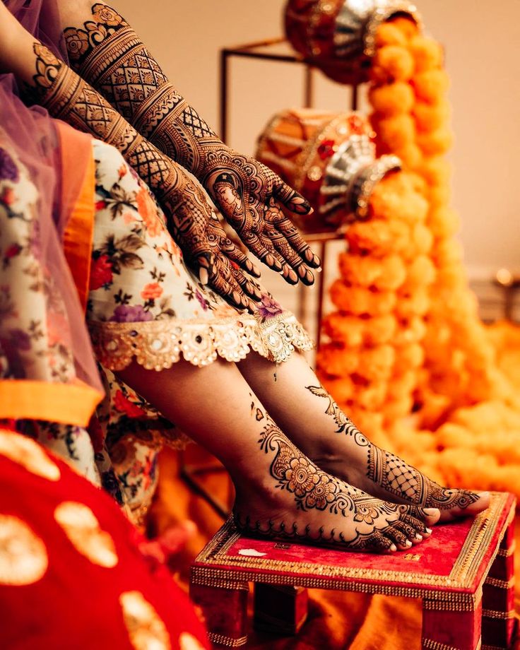 two women with henna tattoos on their feet and legs sitting next to each other