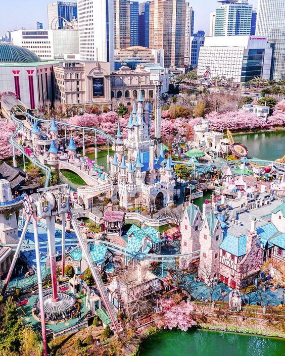 an aerial view of the amusement park with cherry blossom trees and buildings in the background