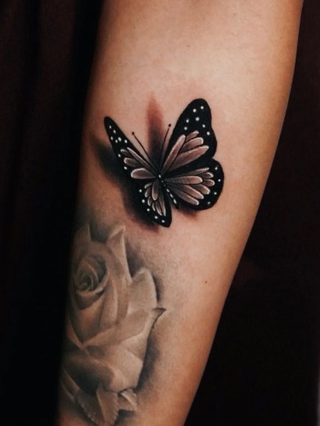 a black and white tattoo with a butterfly on it's arm next to a rose