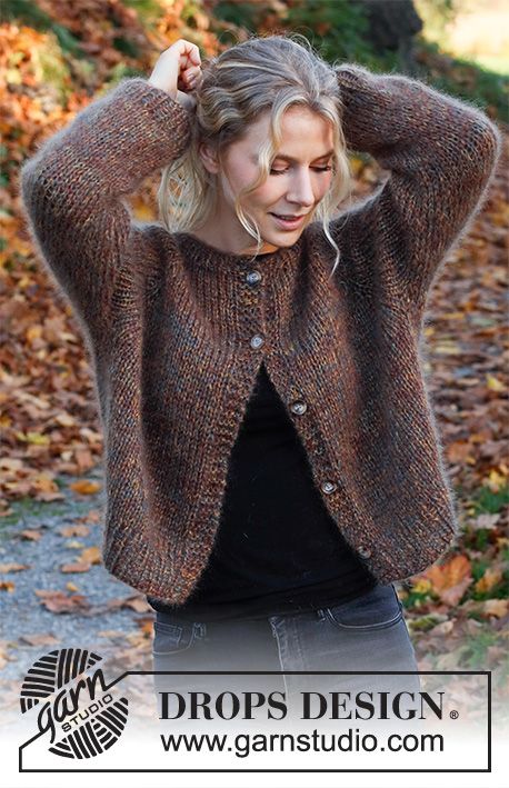 a woman wearing a brown cardigan and black top standing in front of some leaves