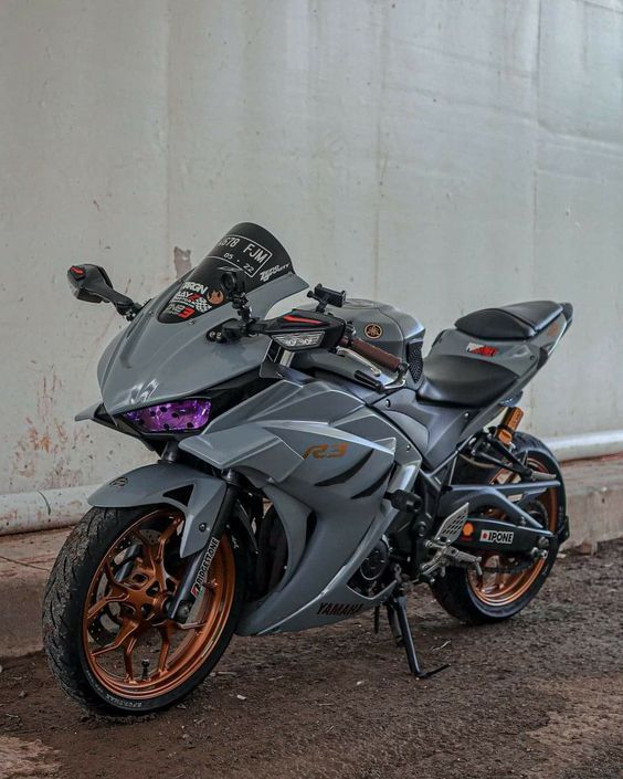 a motorcycle parked in front of a building on the side of the road with orange rims