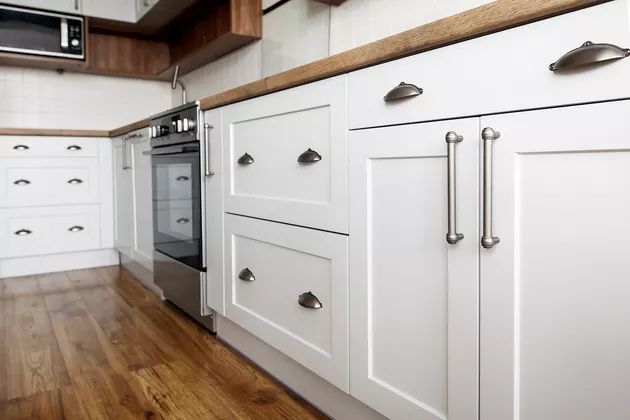 an empty kitchen with white cabinets and wood floors