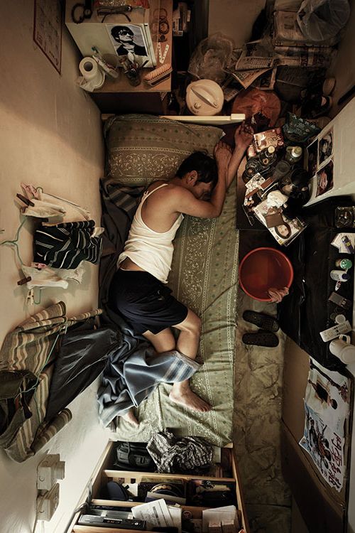 a man laying on top of a bed next to a drawer filled with clutter