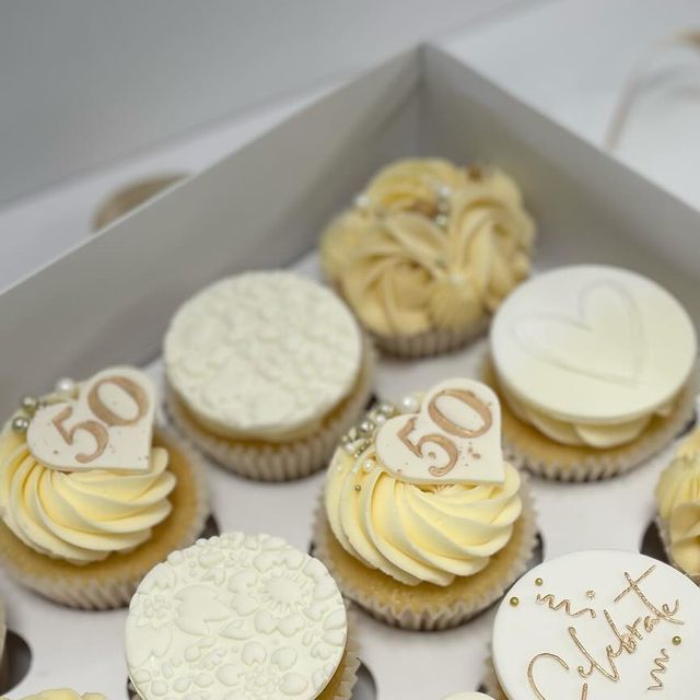 a box filled with lots of cupcakes covered in white frosting and icing