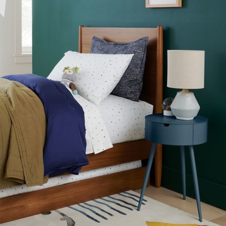 a bedroom with green walls and white polka dots on the bedding, along with a blue night stand