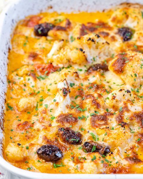 a casserole dish with chicken, cheese and olives in a white bowl