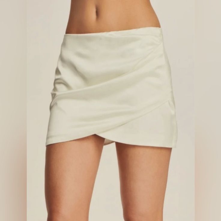 This Ten By Babaton Skirt In Soft Ivory Features A Faux Wrap Style With A Flattering Straight And Pencil Design. The Skirt Is Accented With A Zipper For Added Style. The Size 2 Skirt Has Side Rushing And Is Brand New Without Tags. Originally Priced At $149, This Skirt Is Perfect For Any Occasion And Can Be Dressed Up Or Down. Please Note The First Picture On The Listing Is A Stock Photo The Actual Skirt You Will Receive Is Shown On The Rest Of The Photos Length 17 1/2 Inches Waist 12 Inches Chic White Mini Skirt For Date Night, Elegant Beige Party Skort, Elegant Mini Skirt With Side Zipper, White Fitted Mini Skirt For Date Night, Chic Fitted White Mini Skirt, Chic Mini Skirt With Side Zipper For Spring, Chic White Fitted Mini Skirt, Elegant Pencil Skirt Skort For Date Night, Elegant White Asymmetrical Skort