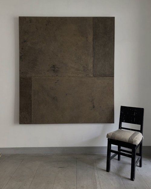 a chair sitting in front of a painting on the wall