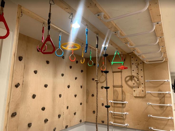 there are many different tools hanging from the ceiling in this room with climbing ropes on the wall