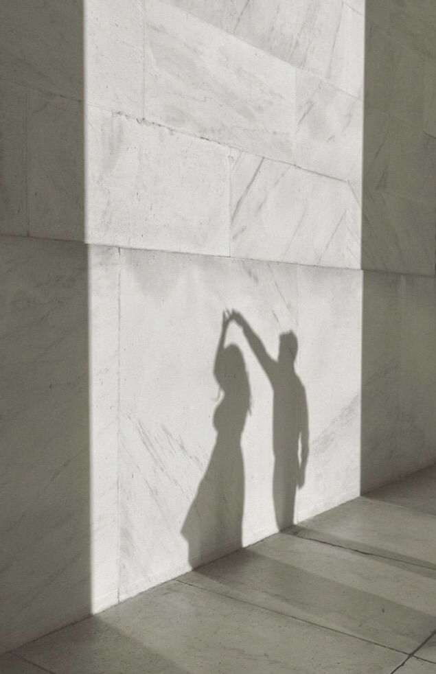 the shadow of a person reaching up against a wall