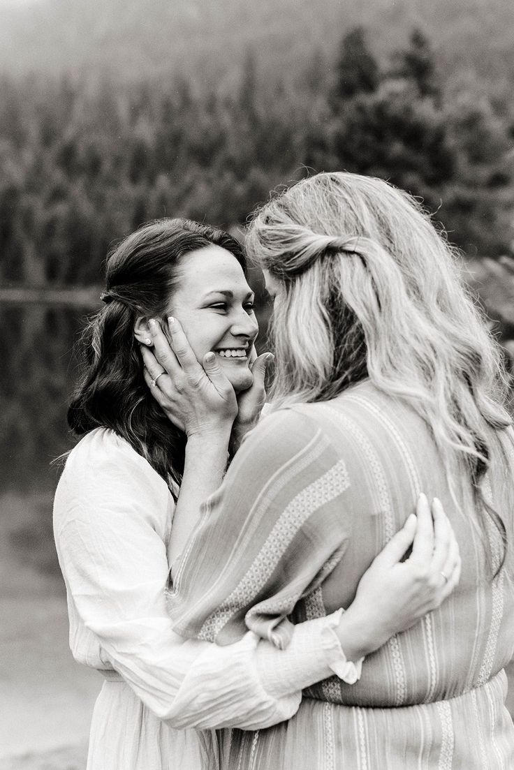 two women hugging each other in front of trees