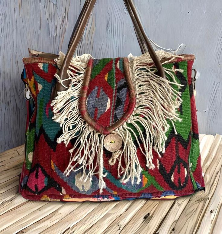 Add a unique piece to your winter outfit style with a bohemian carry-all large tote with tassels colored with natural root dyes in a hand-woven traditional wool rug. Handle and upper part are made of genuine leather. You can remove the strap according to your daily style. You can use this purse as a shoulder bag or handbag. Shoulder strap is adjustable. Suitable for using as a crossbody bag. Together with the bag, we will send two straps, one in real leather and one in guitar strap. You can use Bohemian Multicolor Travel Satchel, Brown Bohemian Satchel With Fringe, Bohemian Brown Hobo Bag, Bohemian Natural Shoulder Bag With Double Handle, Bohemian Multicolor Satchel Bag, Bohemian Natural Color Bags With Double Handle, Bohemian Brown Fringe Satchel, Brown Bohemian Fringe Satchel, Bohemian Double Handle Natural Bag