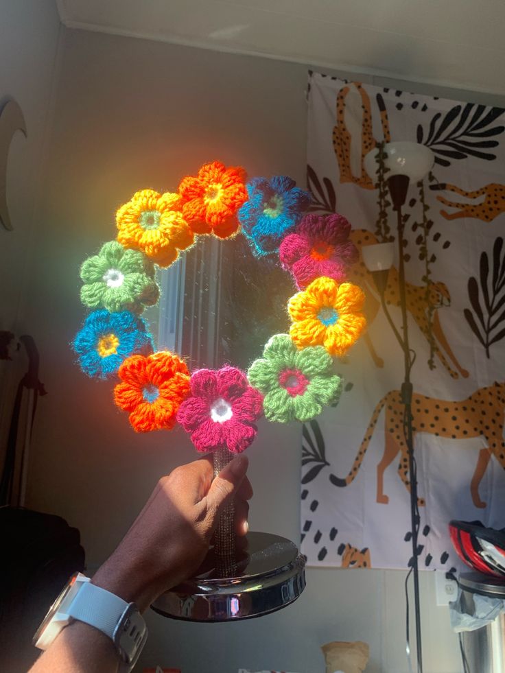 a person is holding up a crocheted wreath