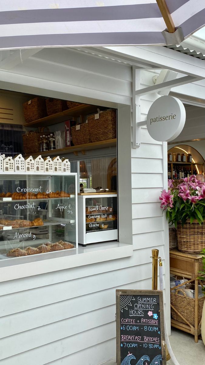 the outside of a bakery with flowers and baskets