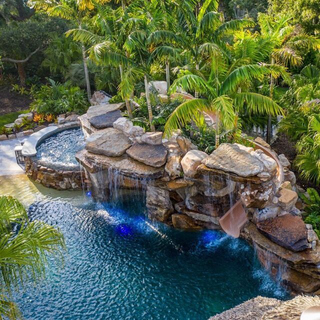 an aerial view of a pool with waterfall and water features in the middle surrounded by palm trees