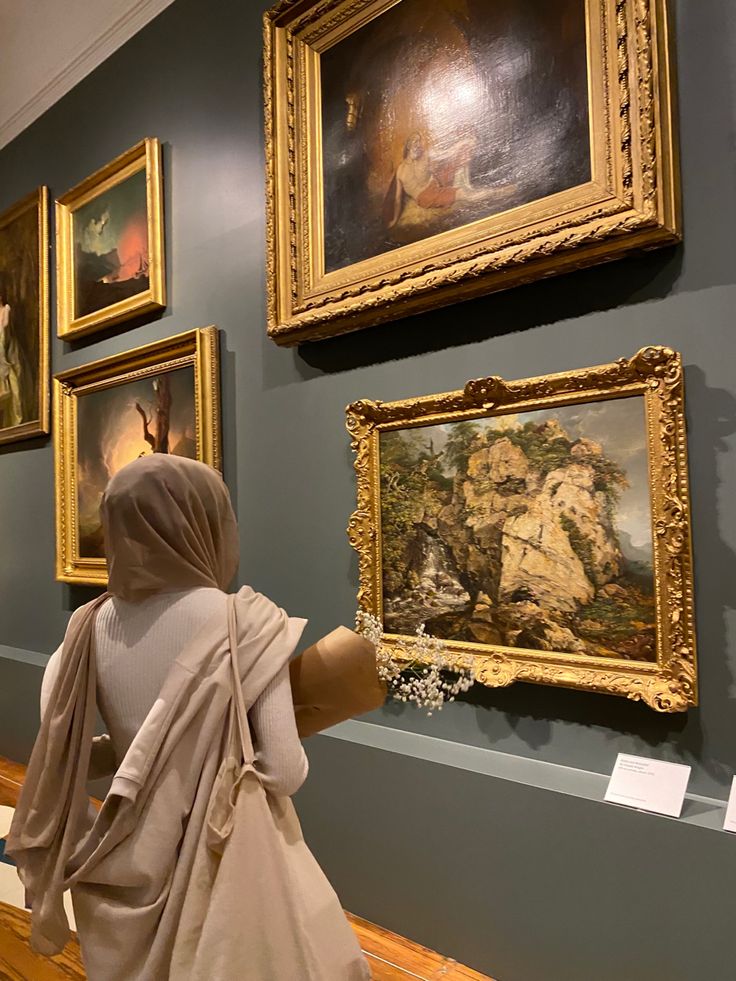 a woman is looking at paintings on the wall