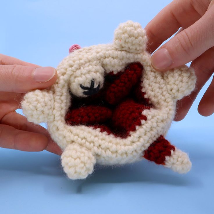 two hands holding a small crocheted teddy bear